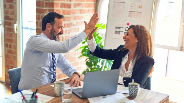 Dos personas felices usando laptop para revisar sus deducciones personales