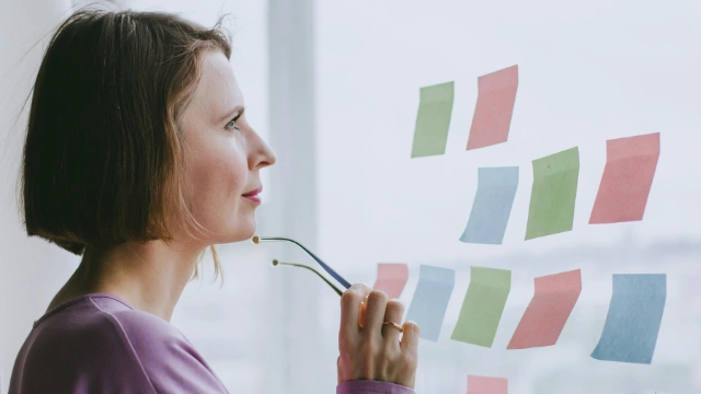 Mujer pensando frente a post-its de colores sobre qué seguro médico cubrirá su preexistencia