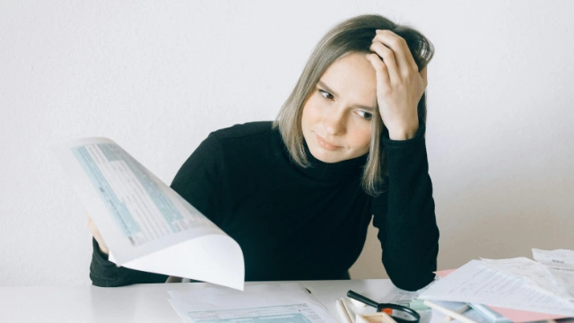 Woman looking frustrated while reviewing documents, unsure about which health insurance will cover her preexisting condition