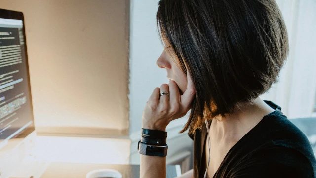 Mujer leyendo información financiera en su computadora acerca de renta fija vs renta variable