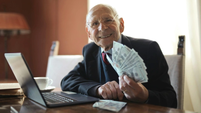 Hombre mayor sosteniendo billetes con una sonrisa, representando los beneficios de invertir a largo plazo.