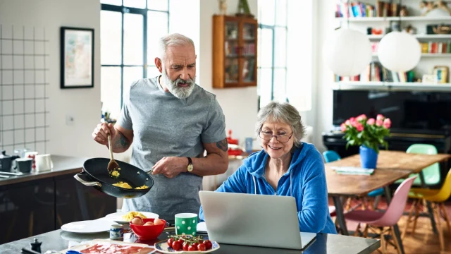 Pareja adulta mayor cocinando juntos en una cocina moderna, mostrando salud y bienestar en la tercera edad
