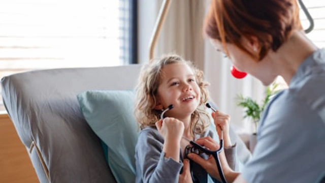 Doctor revisando a una niña feliz en un hospital privado cubierto por su seguro de gastos médicos mayores.