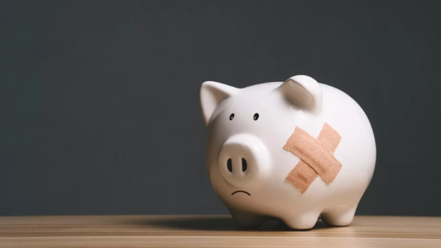 Alcancía triste con dos curitas en forma de X, simbolizando errores financieros que afectan tu retiro