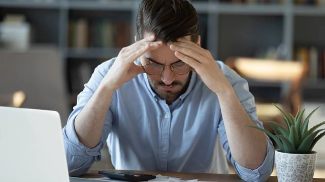 Hombre con expresión de preocupación mirando su laptop, representando la incertidumbre ante posibles fraudes financieros.
