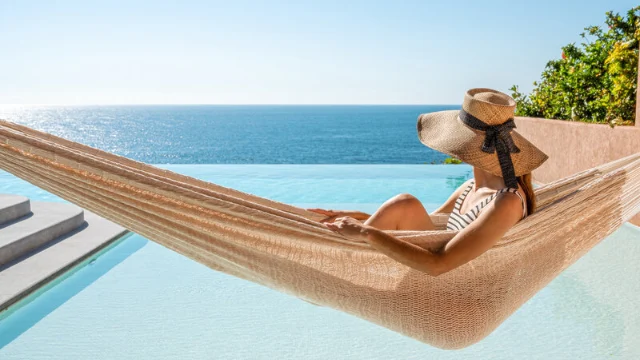 A woman resting in a hammock at a luxury beachfront hotel in Mexico, symbolizing tax-efficient investing and retirement freedom.
