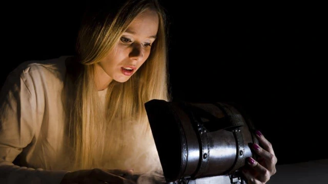 Mujer sorprendida abriendo un cofre del tesoro iluminado que representa los beneficios ocultos de un PPR y un plan personal de retiro bien estructurado