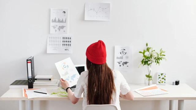 Mujer freelancer de espaldas trabajando en su escritorio analizando opciones de PPR para freelancers y RESICO desde casa