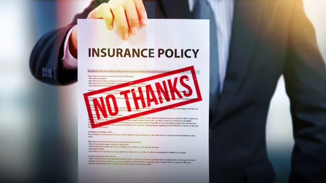 Man holding an insurance policy with a red stamp that says “no thanks”