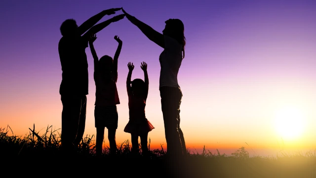 Familia protegiendo a sus hijos debajo de sus brazos como representación visual de la cobertura de un seguro de vida.