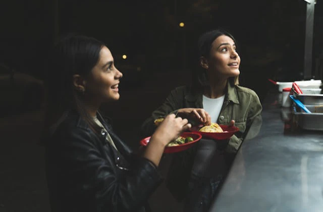Two women eating tacos at a Mexican street food stand during the World Cup.