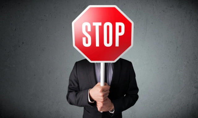 Man holding a red stop sign representing the maximum coinsurance amount in a Mexican health insurance policy.